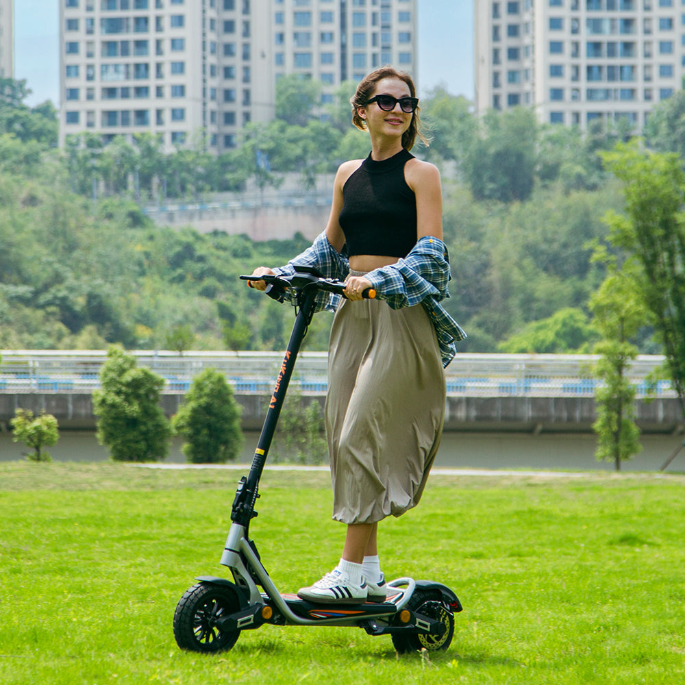 Rider using a silver KuKirin A1 electric scooter in a park