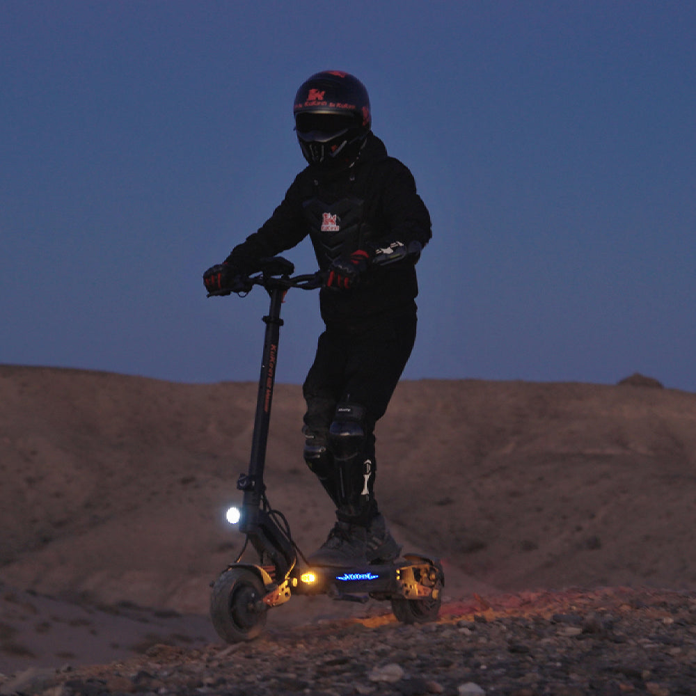 Helmeted rider using a lit KuKirin G2 Master electric scooter at night