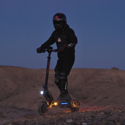Helmeted rider using a lit KuKirin G2 Master electric scooter at night